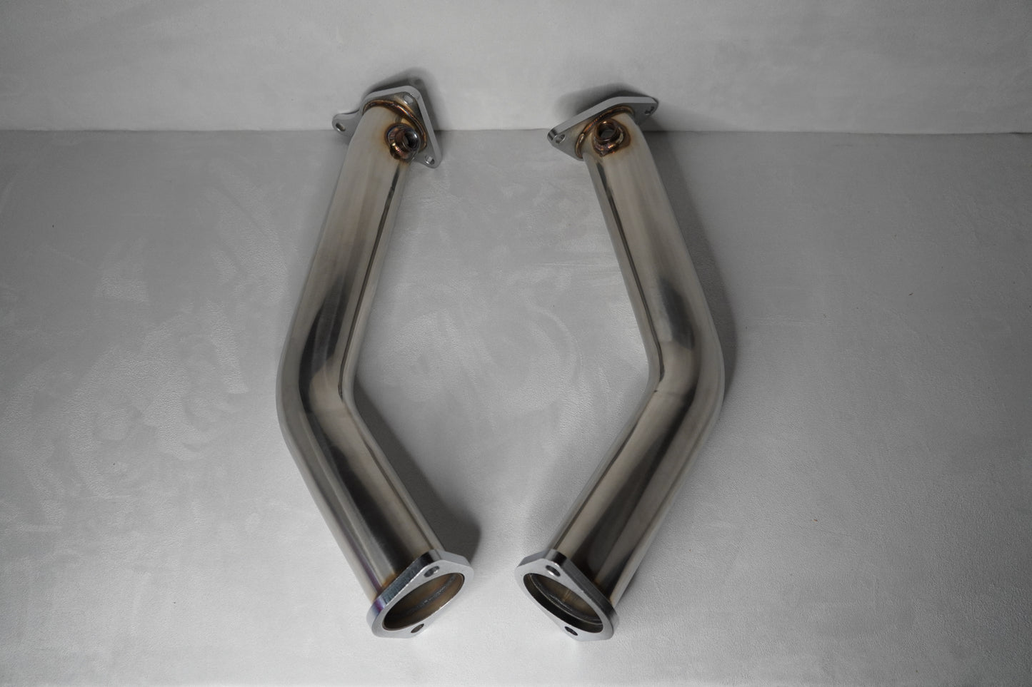 Two chrome exhaust pipes on a gray background