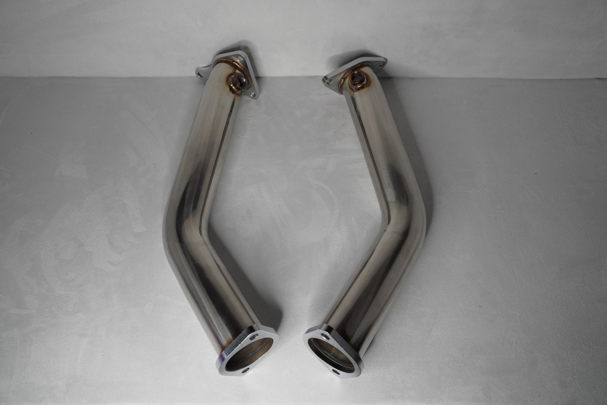 Two chrome exhaust pipes on a gray background